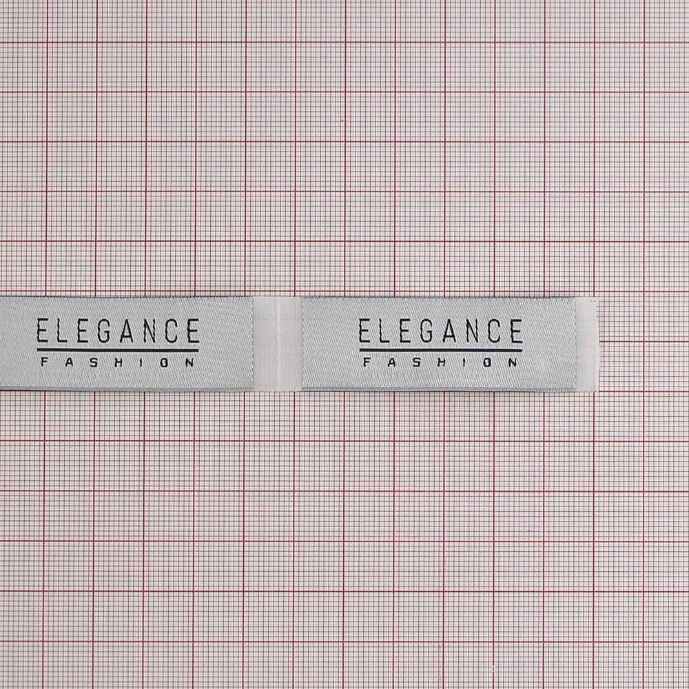 Этикетка тканевая вышитая Elegance №7, 2*6,5см, светло-серая и черный лого /70 atki/, шт. Вышивка / этикетка тканевая