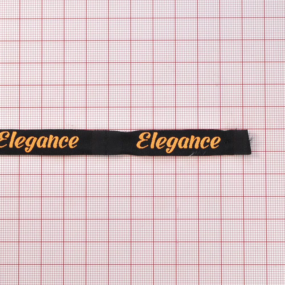 Этикетка тканевая вышитая Elegance №13, 1,2*6,6см черная, оранжевый лого /70 atki/ . Вышивка / этикетка тканевая